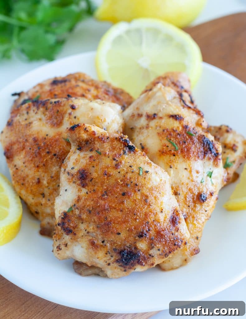 The Ultimate Air Fryer Chicken Thighs 2 chicken thighs on a plate with lemons
