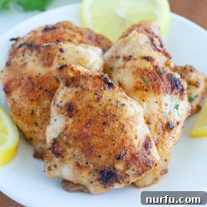 The Ultimate Air Fryer Chicken Thighs 5 chicken thighs on a plate with lemons