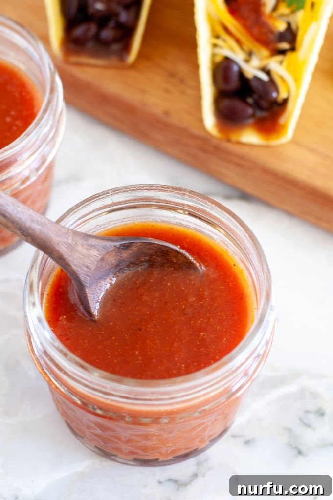 Fiesta Flavor Sauce 4 Jar of homemade taco sauce with a wooden spoon, ready to be served or stored.