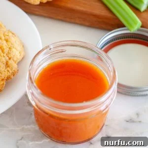 A jar filled with vibrant red buffalo sauce, ready to be used or stored.