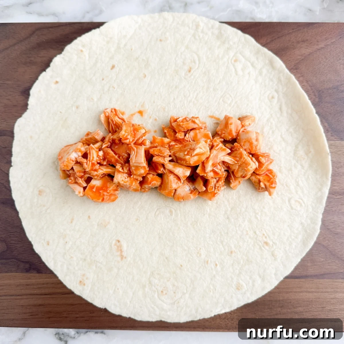 Zesty Buffalo Chicken Wraps 5 Tortilla with buffalo chicken on top.