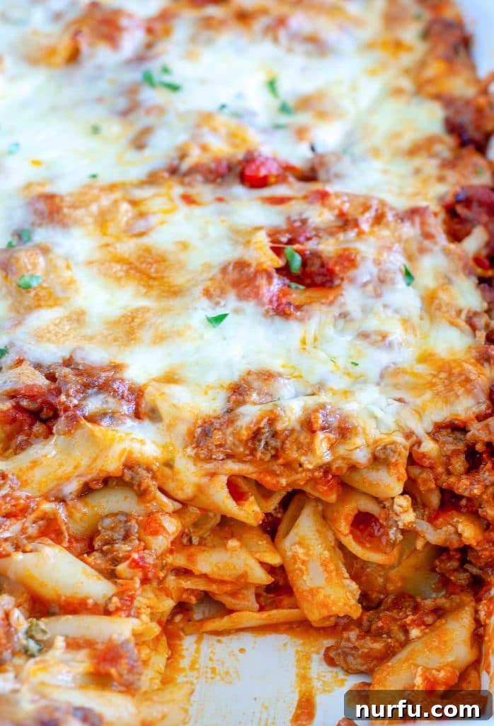 Cheesy Baked Mostaccioli 2 Mostaccioli in a casserole dish, a vibrant red sauce with melted cheese and herbs.