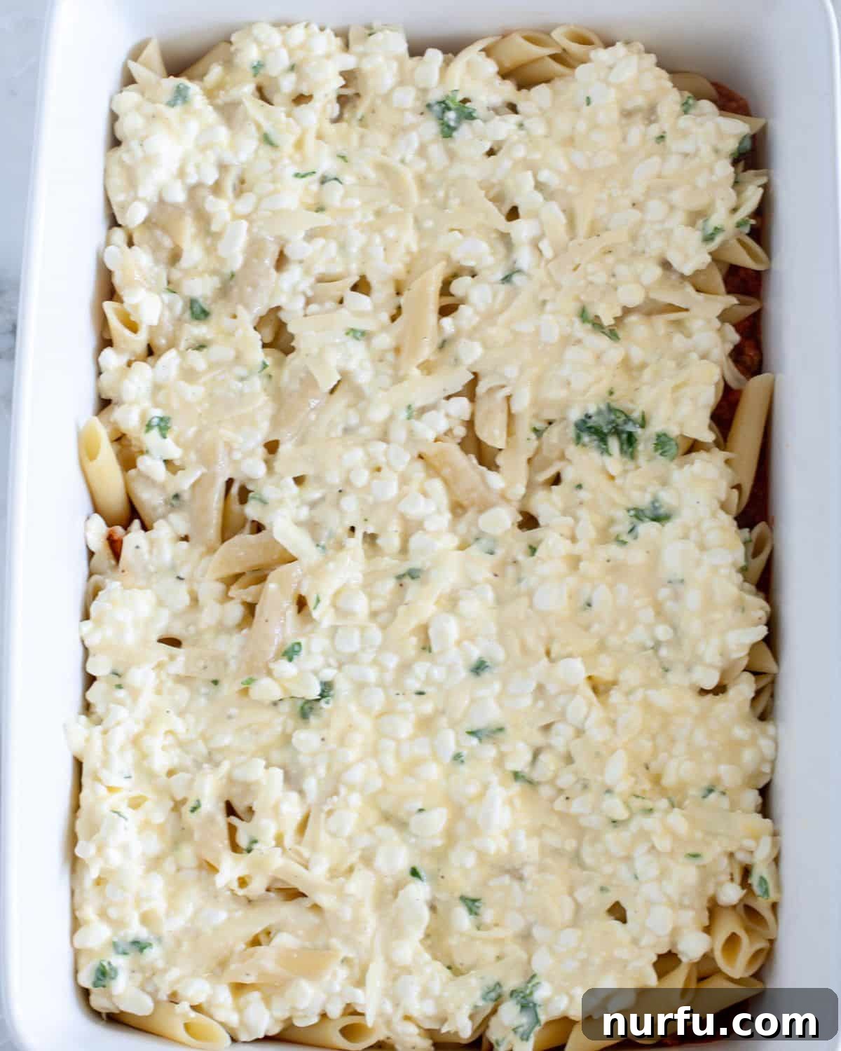 Cheesy Baked Mostaccioli 5 Topping the first layer of sauce with half of the cooked mostaccioli pasta in a baking dish.