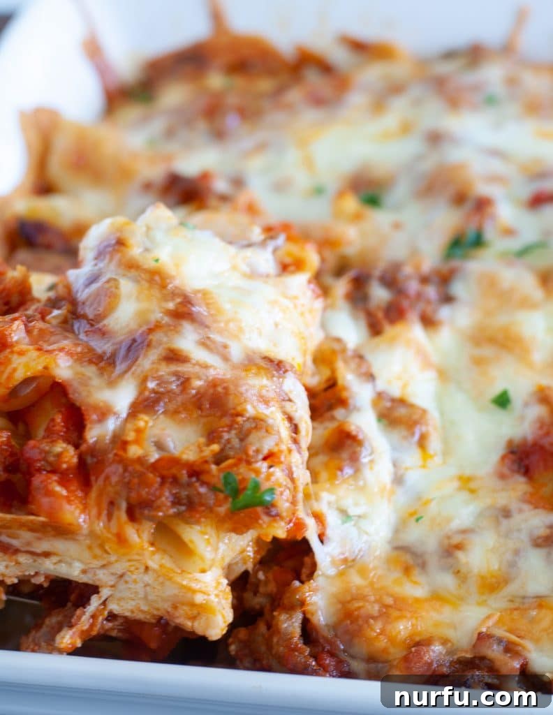 Cheesy Baked Mostaccioli 8 A spatula lifting a perfect piece of baked mostaccioli from the casserole dish, showing the layers of pasta, sauce, and cheese.