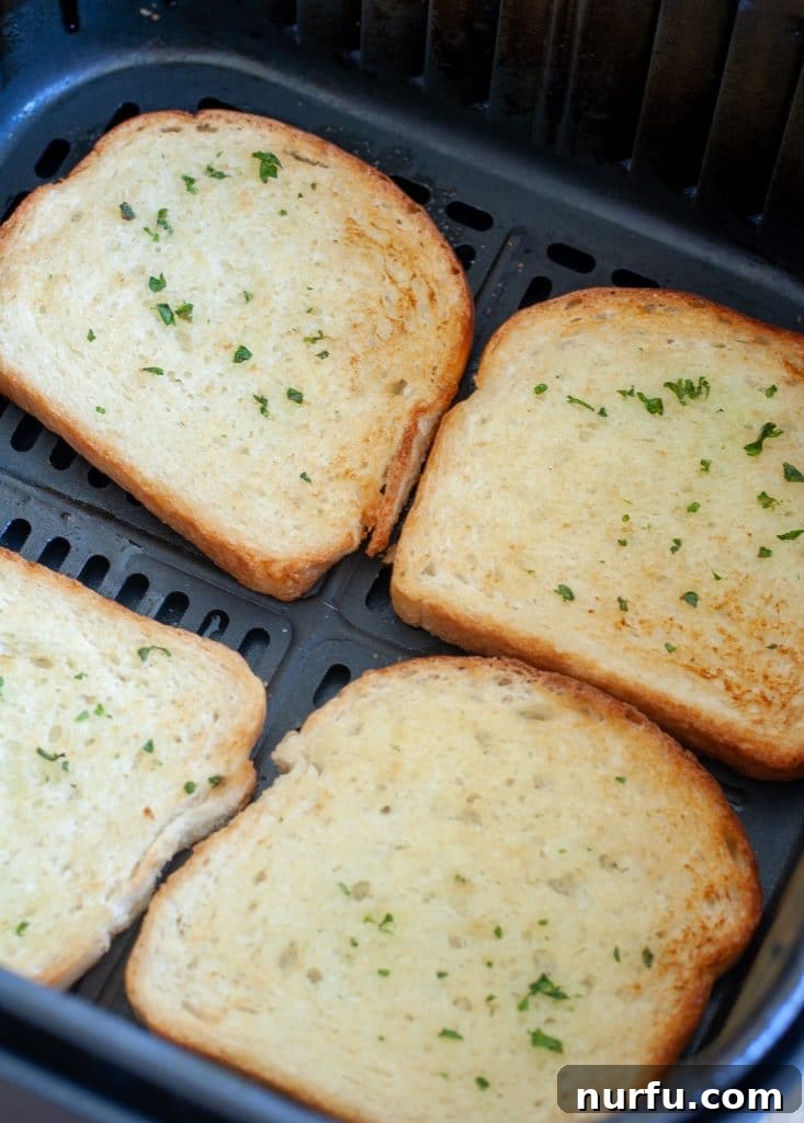 Perfect Air Fryer Texas Toast 4 Freshly cooked, golden-brown Texas toast slices arranged in a single layer inside an air fryer basket, steam gently rising.