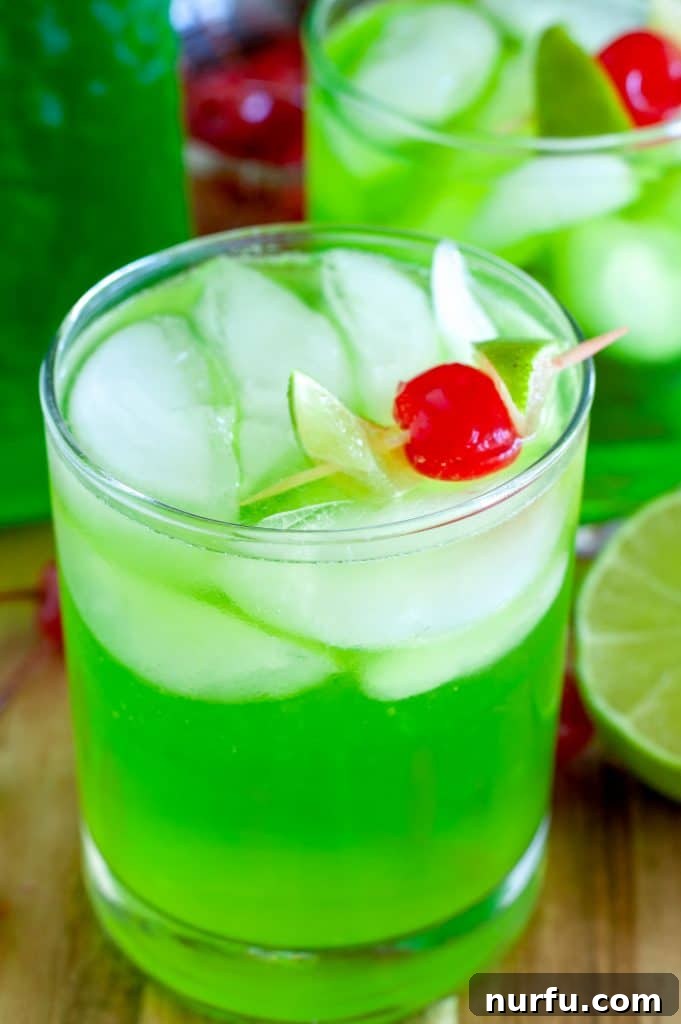 A vibrant green Midori Sour cocktail in a glass, garnished with a bright red maraschino cherry and a lime wedge.