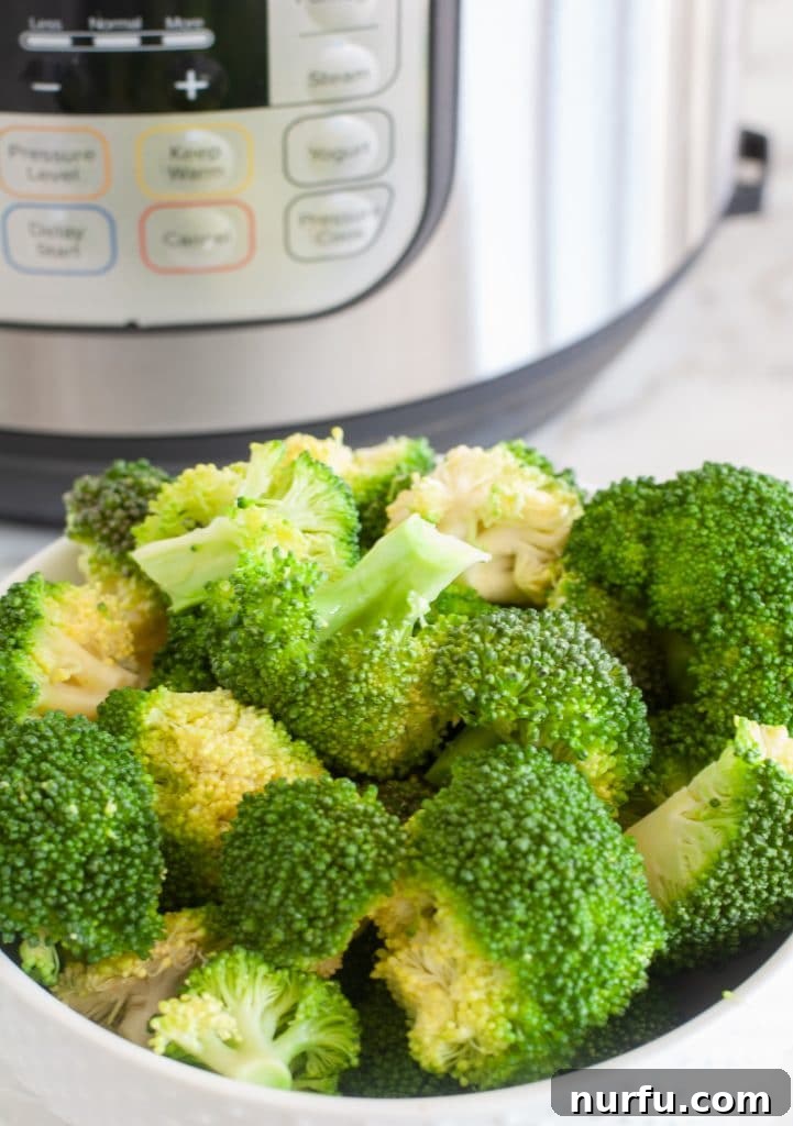 Quick and Tender Instant Pot Broccoli 4 A bowl of perfectly steamed Instant Pot broccoli next to the Instant Pot.