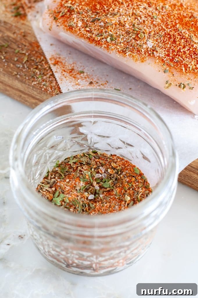 Ultimate Chicken Flavor Mix 4 Spices in a jar with a piece of chicken and seasonings