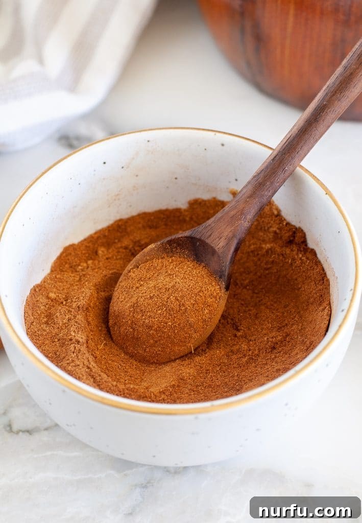 Signature Pumpkin Spice Blend 4 A bowl of freshly mixed pumpkin pie spice with a spoon, ready for use.