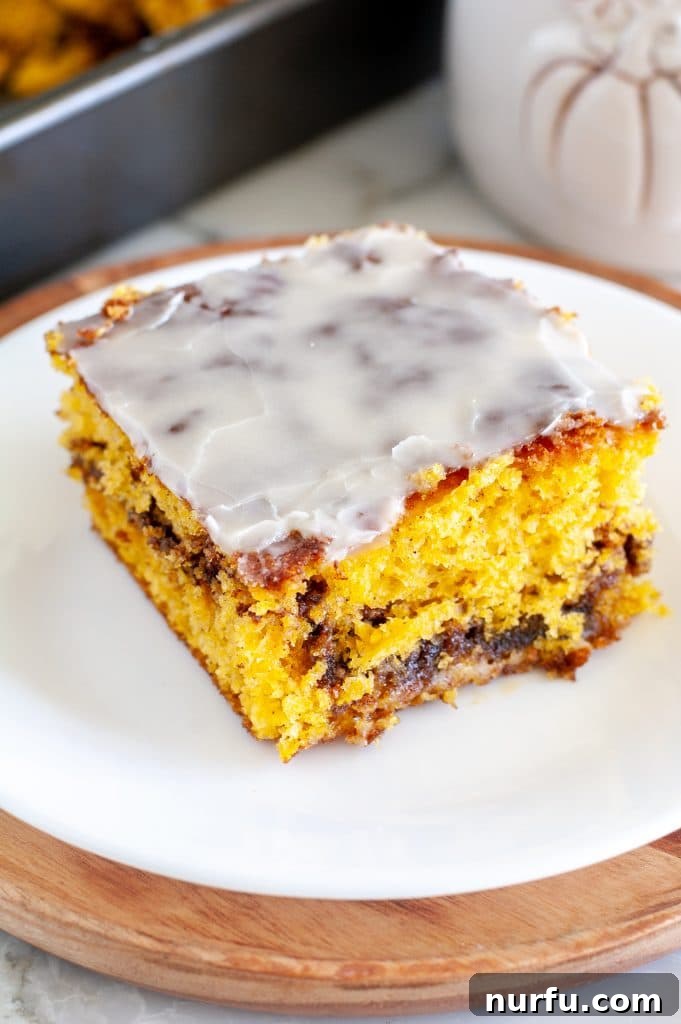 Autumn Spiced Pumpkin Coffee Cake 2 Coffee cake on a plate, garnished with a sprinkle of powdered sugar and a fork, ready to be enjoyed.
