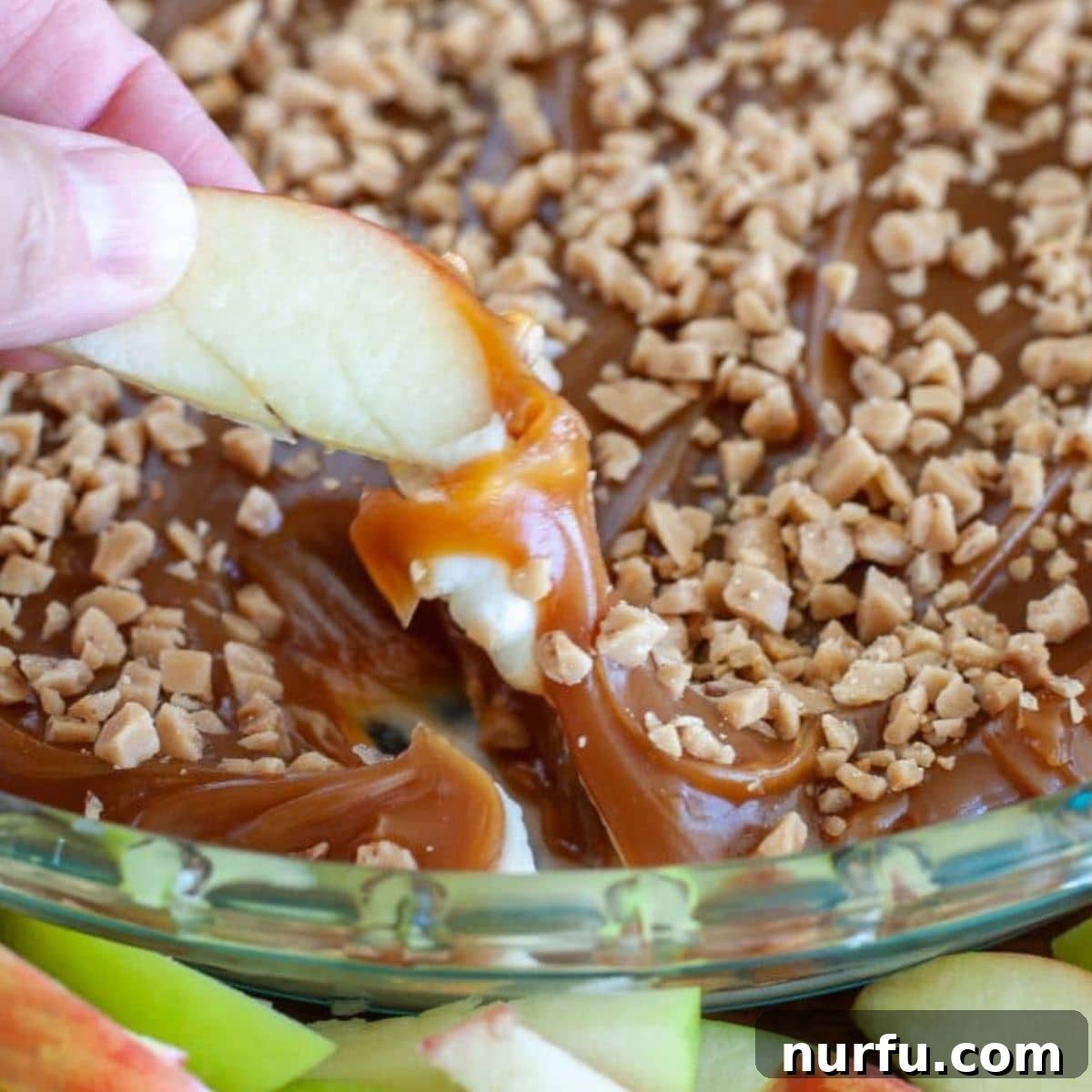 Heavenly Caramel Apple Dip 6 Caramel Apple Dip served in a shallow dish, topped with toffee bits, with apple slices around it.