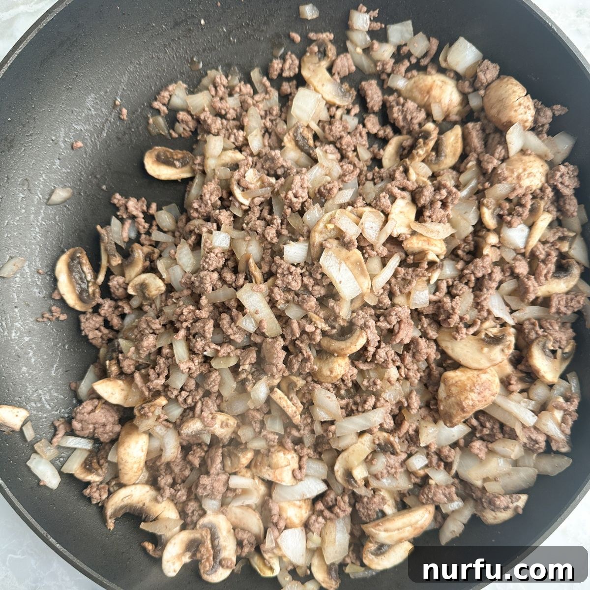 Homemade Skillet Stroganoff with Noodles 4 Skillet with ground beef, onions, and mushrooms browning.