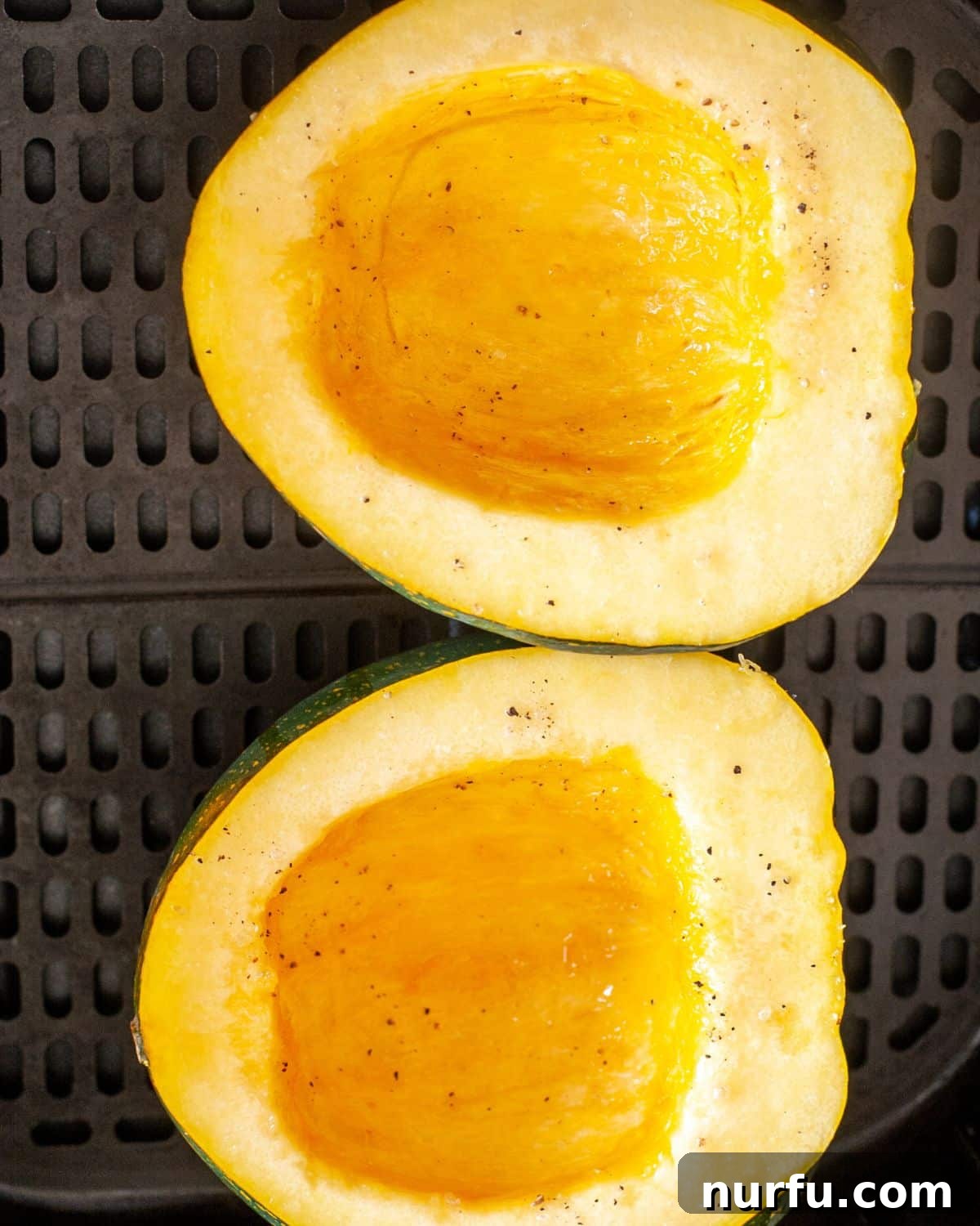 Savory and Sweet Air Fryer Acorn Squash 4 Two halves of acorn squash placed cut-side up in an air fryer basket, ready for cooking.