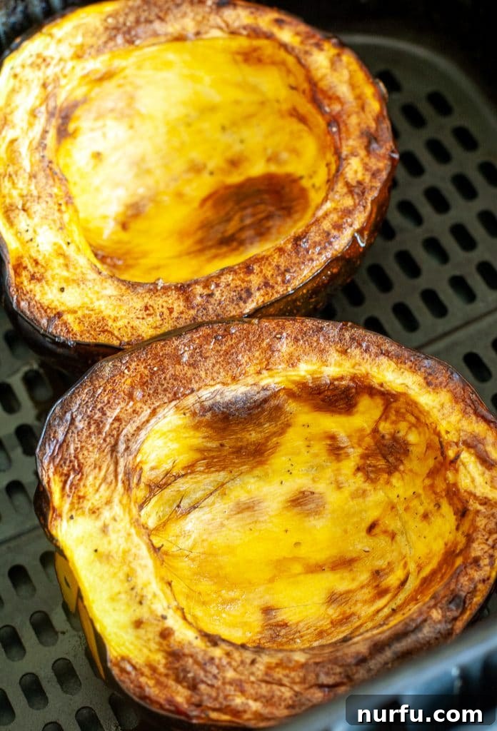 Savory and Sweet Air Fryer Acorn Squash 5 Cooked acorn squash halves with crispy, caramelized edges, served in an air fryer basket.