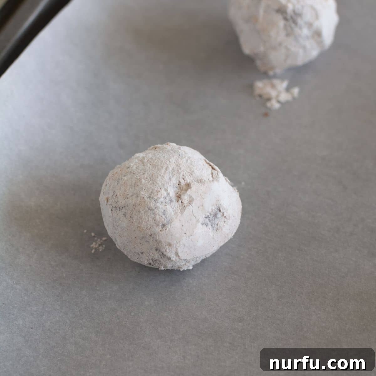 Spiced Chocolate Crinkle Delights 5 Perfectly coated chocolate cinnamon cookie dough balls arranged neatly on a baking sheet lined with parchment paper, spaced for optimal baking.