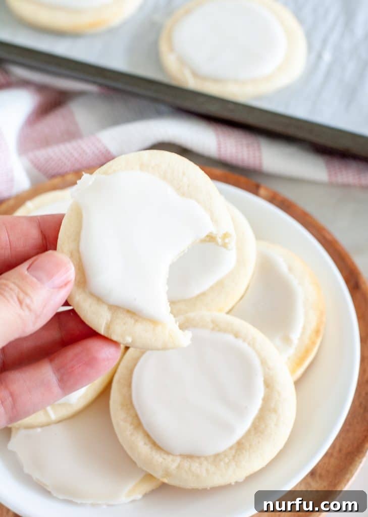 Pillowy Soft Sour Cream Cookies 4 Hand holding a frosted sour cream cookie with a bite taken out