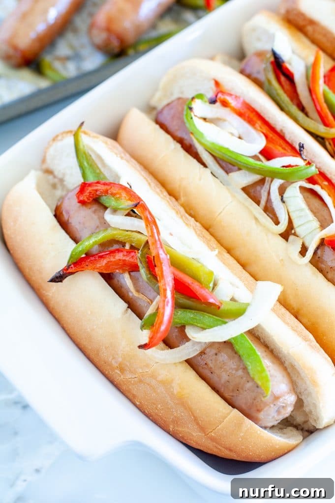 Golden Oven Brats 2 Sausage in a roll with peppers and onions, showcasing the delicious oven-baked bratwurst meal.