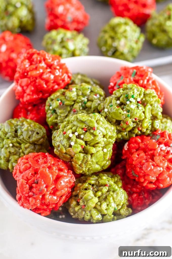 Festive Crispy Delights 2 A bowl filled with festive red and green Christmas Rice Krispie treat balls, adorned with colorful sprinkles, sitting on a wooden surface.
