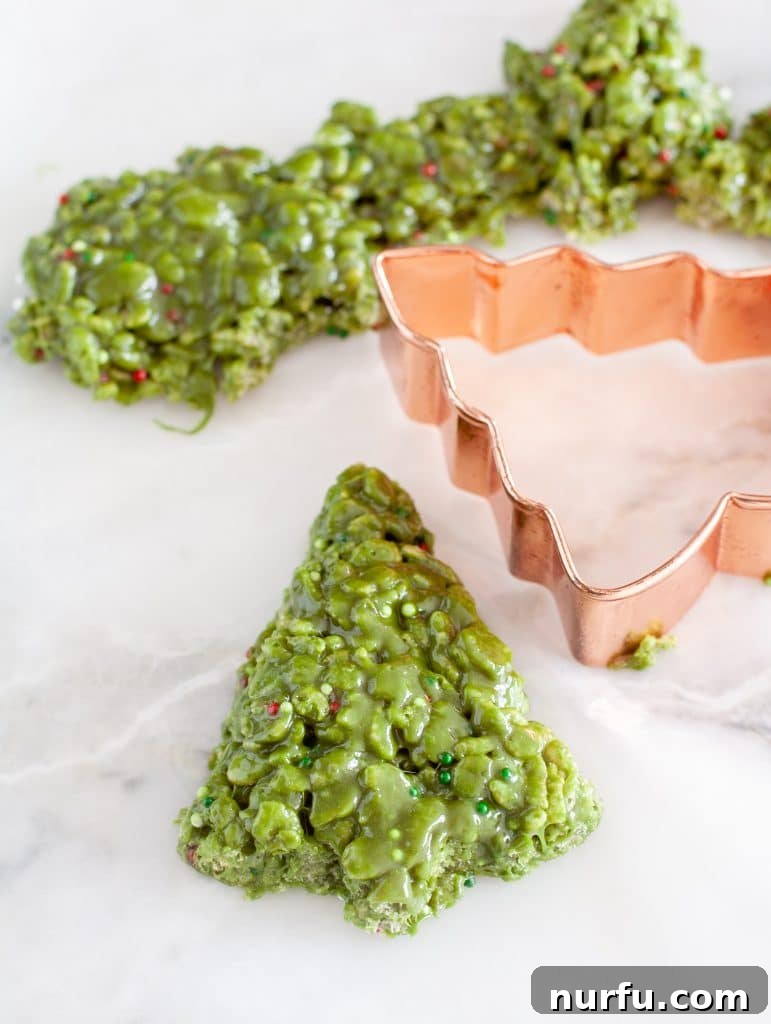 Festive Crispy Delights 4 A Rice Krispie treat shaped like a Christmas tree, cut out with a cookie cutter on parchment paper.
