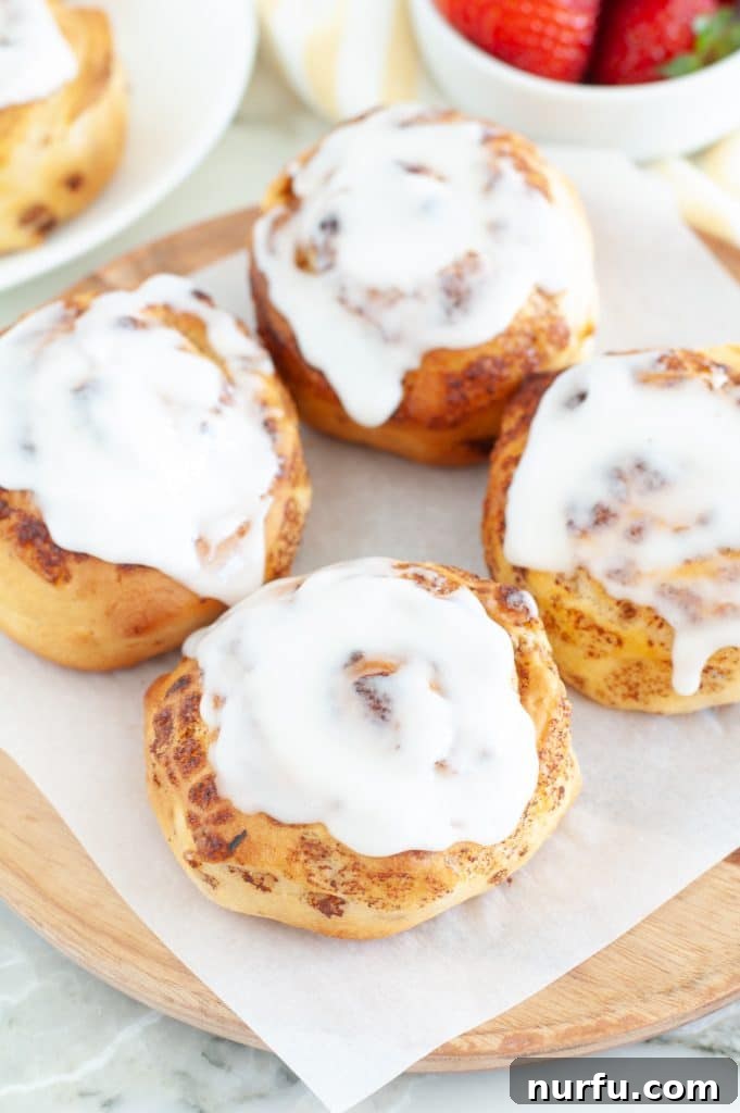 Effortless Air Fryer Cinnamon Buns 2 Freshly baked cinnamon rolls on a plate with icing