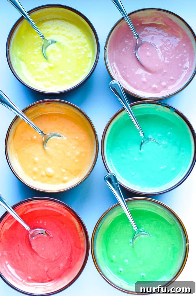 Six bowls of cake batter, each dyed a different color of the rainbow.