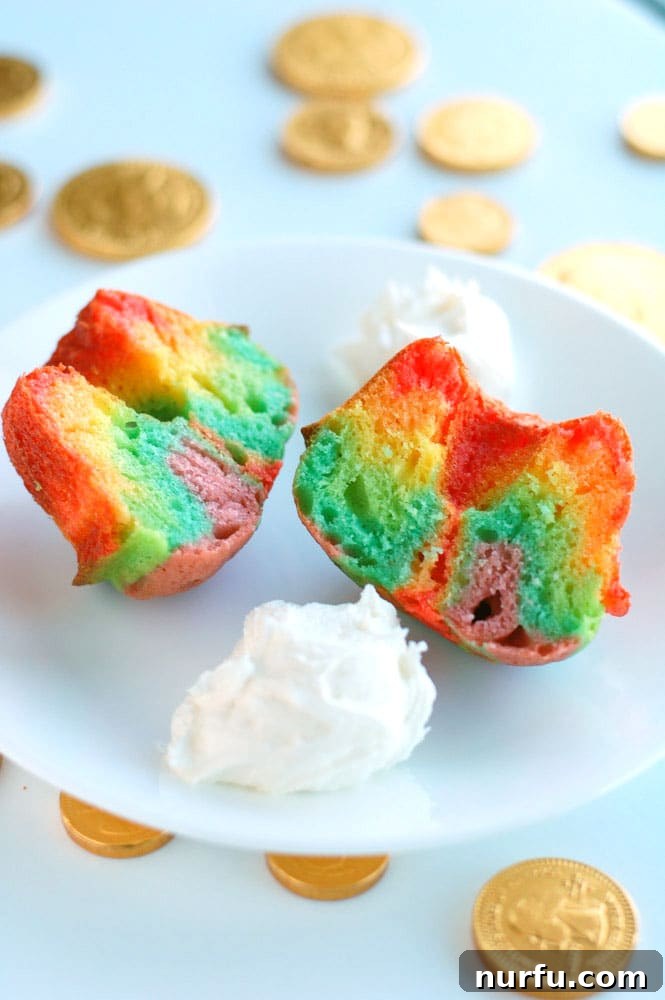 Finished rainbow mini bundt cakes with white marshmallow frosting on a serving platter.