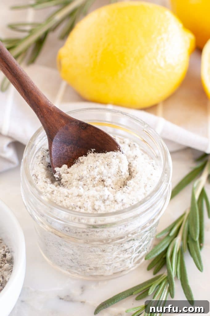 Fragrant Rosemary Salt Blend 2 Salt in a bowl with wooden spoon, featuring fresh rosemary sprigs.