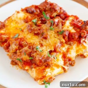 A perfectly portioned slice of no-boil lasagna, showcasing its layers of pasta, rich meat sauce, and melted cheese, served elegantly on a pristine white plate.