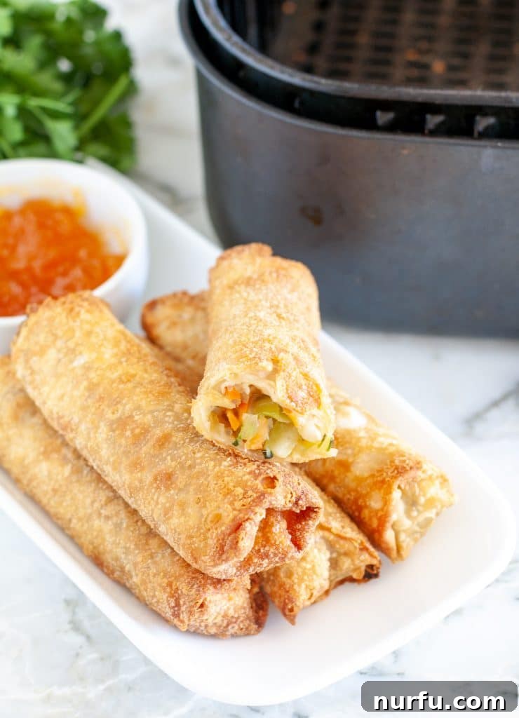 Air Fryer Crispy Egg Rolls: From Freezer to Fantastic 2 Egg rolls on a plate with sauce.