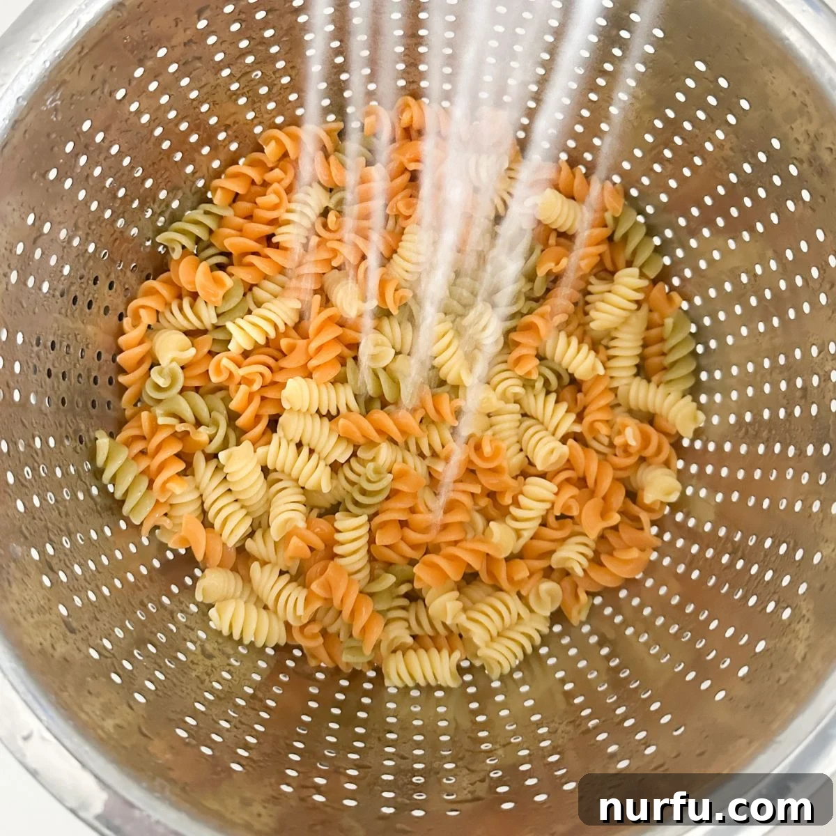 Zesty Pepperoni Pasta Medley 4 Colander with pasta and running water.