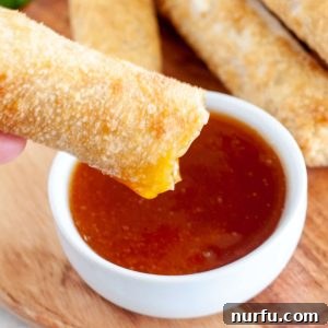 Bowl of sauce with egg roll dipping into it.