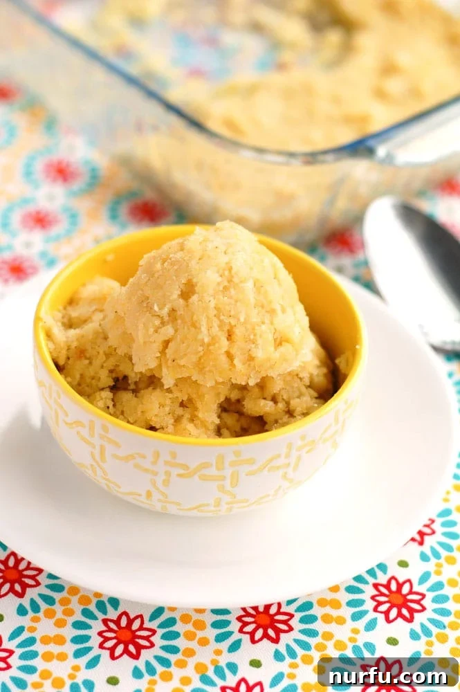 Chi-Chi's Sweet Corn Cake A generous scoop of golden Copycat Chi-Chi's Sweet Corn Cake served in a rustic ceramic bowl, garnished lightly, highlighting its moist texture.