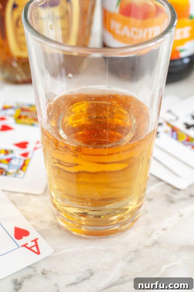 Ignite Your Night: The Vegas Bomb Cocktail 2 Glass with a vibrant energy drink and a shot glass containing mixed liquor, with playing cards casually placed beside it, evoking a Las Vegas casino theme.