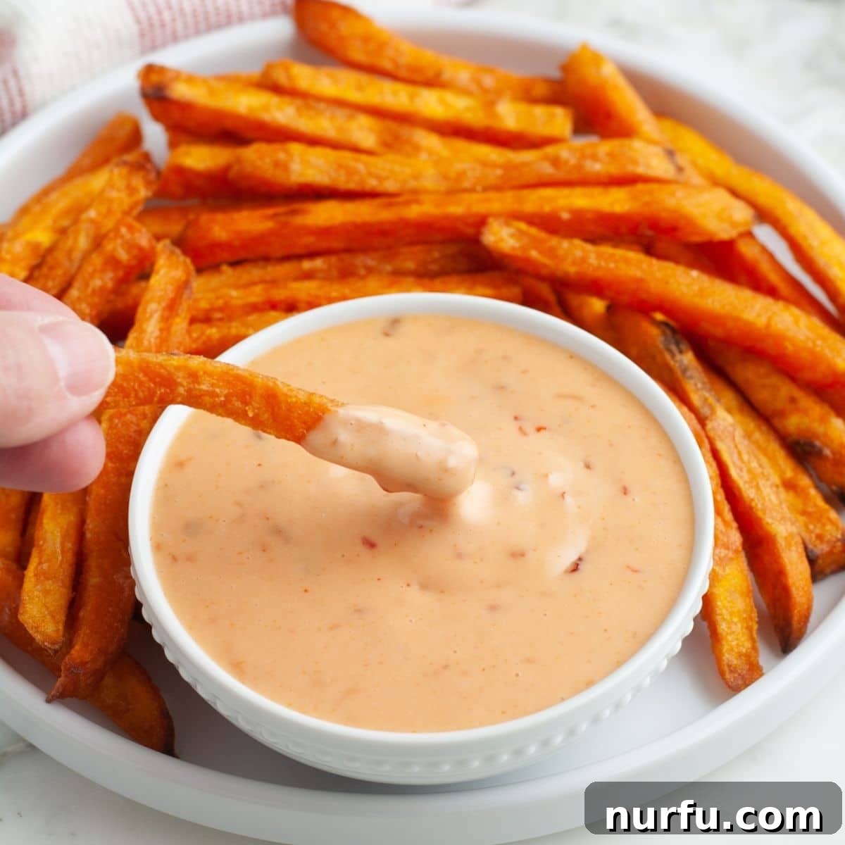 A bowl of boom boom sauce served alongside a pile of perfectly cooked sweet potato fries, ready to be enjoyed.