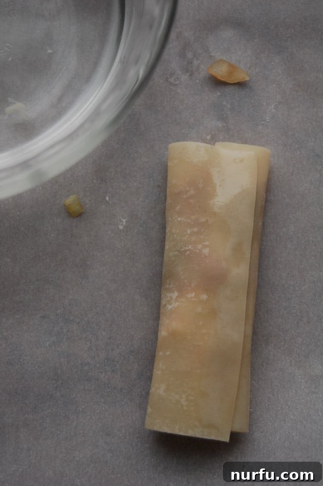 Crispy Vietnamese Spring Rolls with Tropical Pineapple Dip 5 The process of rolling Lumpia, with the bottom corner folded over the filling and side corners tucked in, forming an envelope shape.