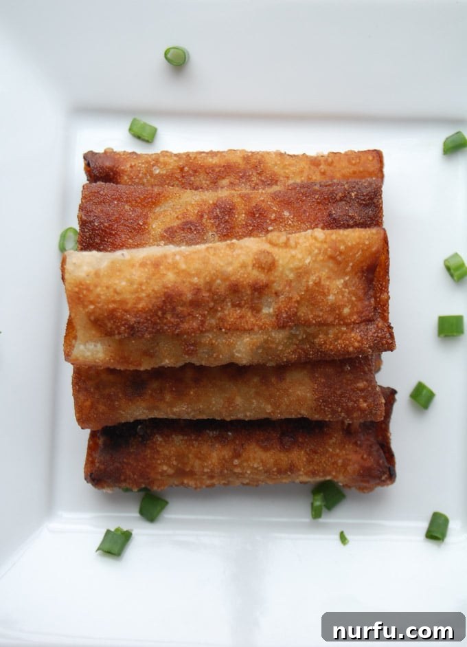 Crispy Vietnamese Spring Rolls with Tropical Pineapple Dip 6 Several perfectly rolled, uncooked Vietnamese Lumpia spring rolls lined up, showcasing the tight seal achieved with water on the seam.