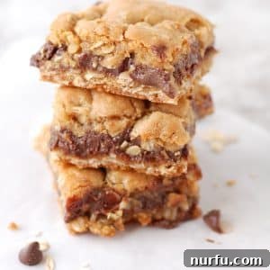 Oatmeal chocolate bar squares stacked on table.