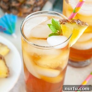 Glass of Hawaiian iced tea with a pineapple slice and mint garnish.