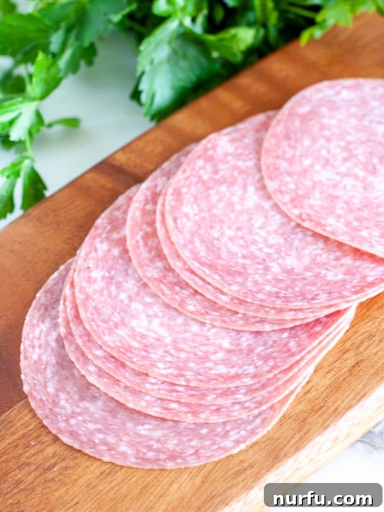 40 Glorious G-Foods 3 Sliced Genoa salami arranged on a cutting board with herbs, ready to be served as an appetizer.