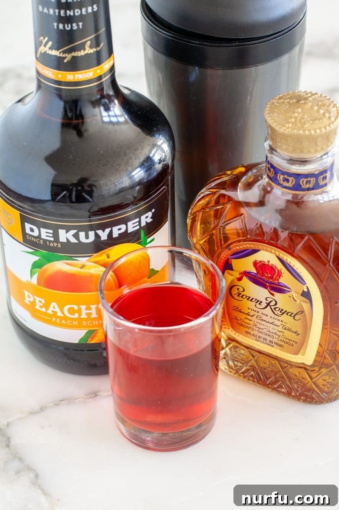 Three essential ingredients for the Royal Flush drink: a bottle of rich Crown Royal whiskey, a bottle of sweet peach schnapps, and a carton of vibrant cranberry juice, arranged on a surface.