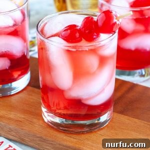 Two glasses showcasing the vibrant red Royal Flush drink, garnished with cherries, ready to be enjoyed.