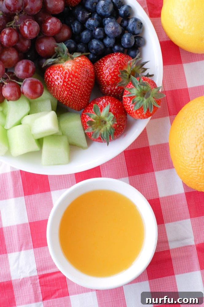 Sunny Orange Dip 3 A close-up shot of a bowl filled with smooth, creamy orange fruit dip, ready to be enjoyed with a variety of fresh fruits like strawberries and grapes.