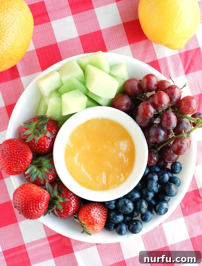 Sunny Orange Dip 5 A close-up of fresh strawberries being dipped into the smooth, orange-colored fruit dip, highlighting its perfect dipping consistency.