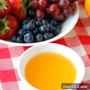 Sunny Orange Dip 6 A vibrant bowl of orange fruit dip nestled amongst a medley of colorful summer fruits, ready for serving.