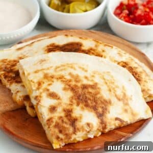 Homemade Taco Bell Chicken Quesadilla Perfection 8 A golden-brown chicken quesadilla, sliced into triangles, presented on a rustic wooden plate.