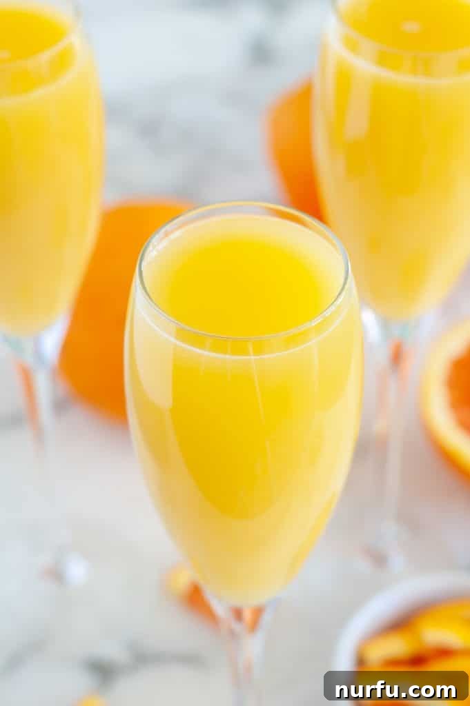 Champagne flute with a vibrant orange juice mimosa mocktail, ready to be enjoyed.