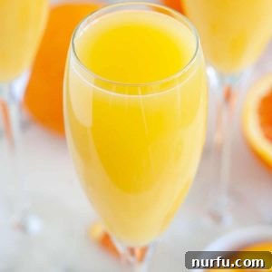 Glass filled with orange juice, ready for a non-alcoholic mimosa.