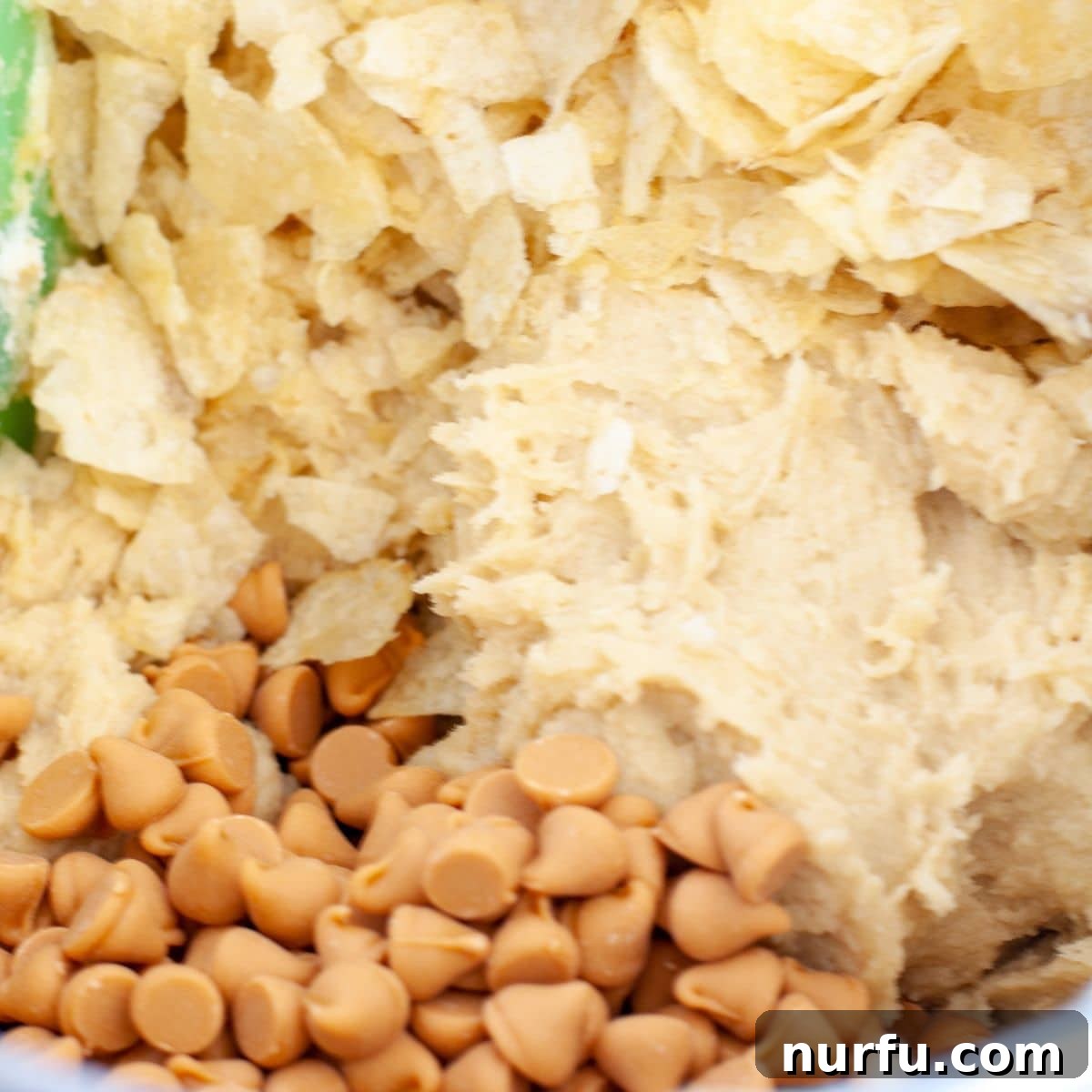 Salty Sweet Chip Crunch Cookies 4 Bowl containing cookie dough mixed with butterscotch chips and crushed potato chips.