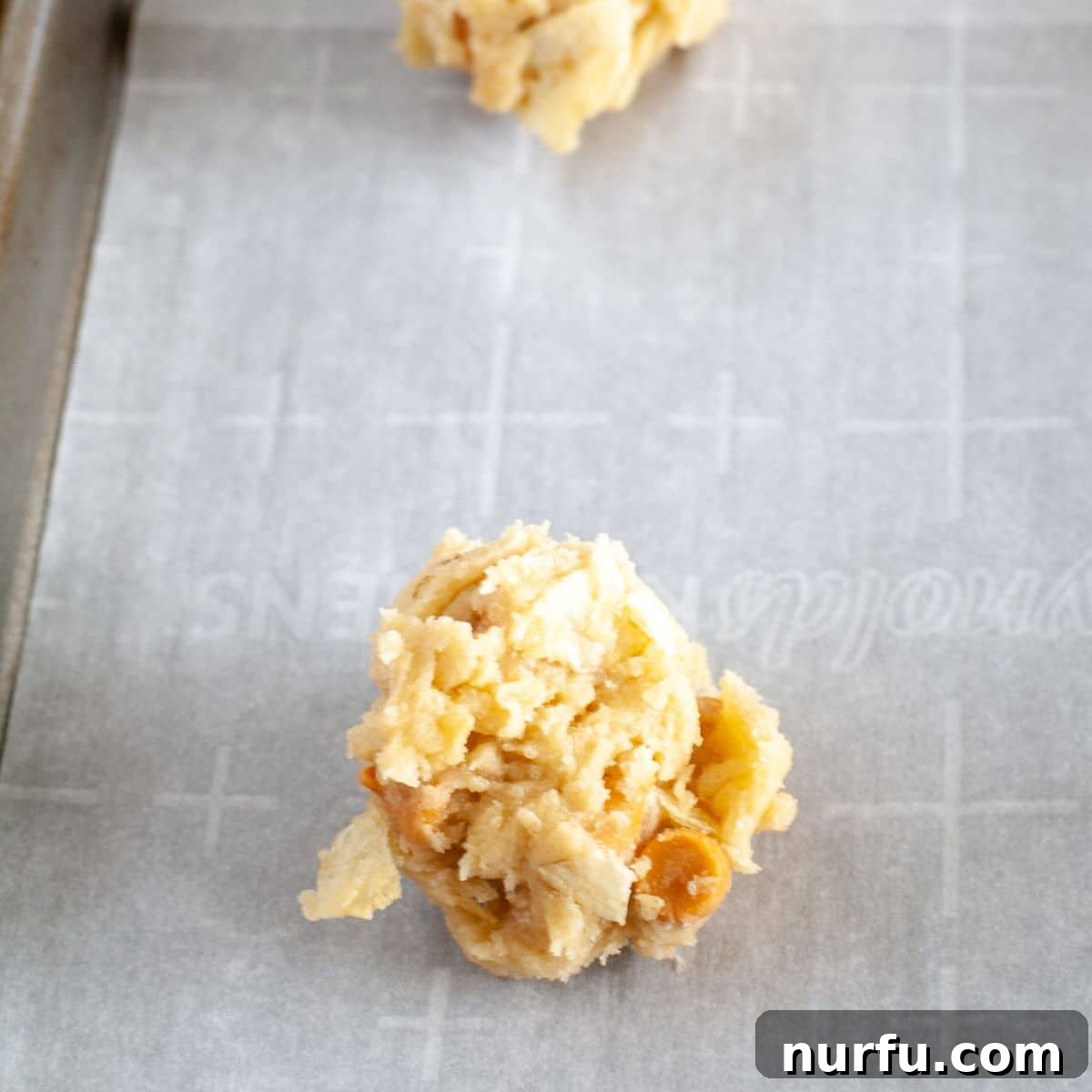 Salty Sweet Chip Crunch Cookies 5 Portion of cookie dough scooped onto a parchment-lined baking pan.