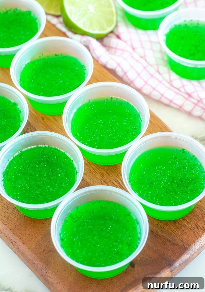 Ultimate Tequila JELL-O Shots 2 Small plastic cups filled with bright green JELLO, ready for a party.